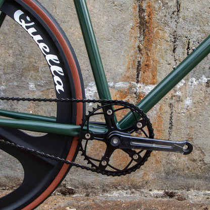 Close-up of a bicycle chain and gear system against a textured wall.
