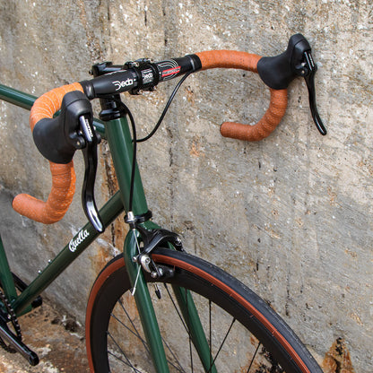 Close-up of a bicycle with orange handlebars against a textured wall.
